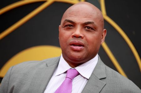 Charles Barkley in a grey suit poses at  a studio.